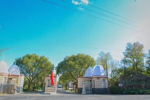 A street view with a row of white domed structures, a red flag, and trees. - An Hengsha Isiand Resort Hotel (Shanghai)