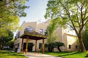 Un edificio con un espacio de asientos techado al aire libre, rodeado de árboles y vegetación.