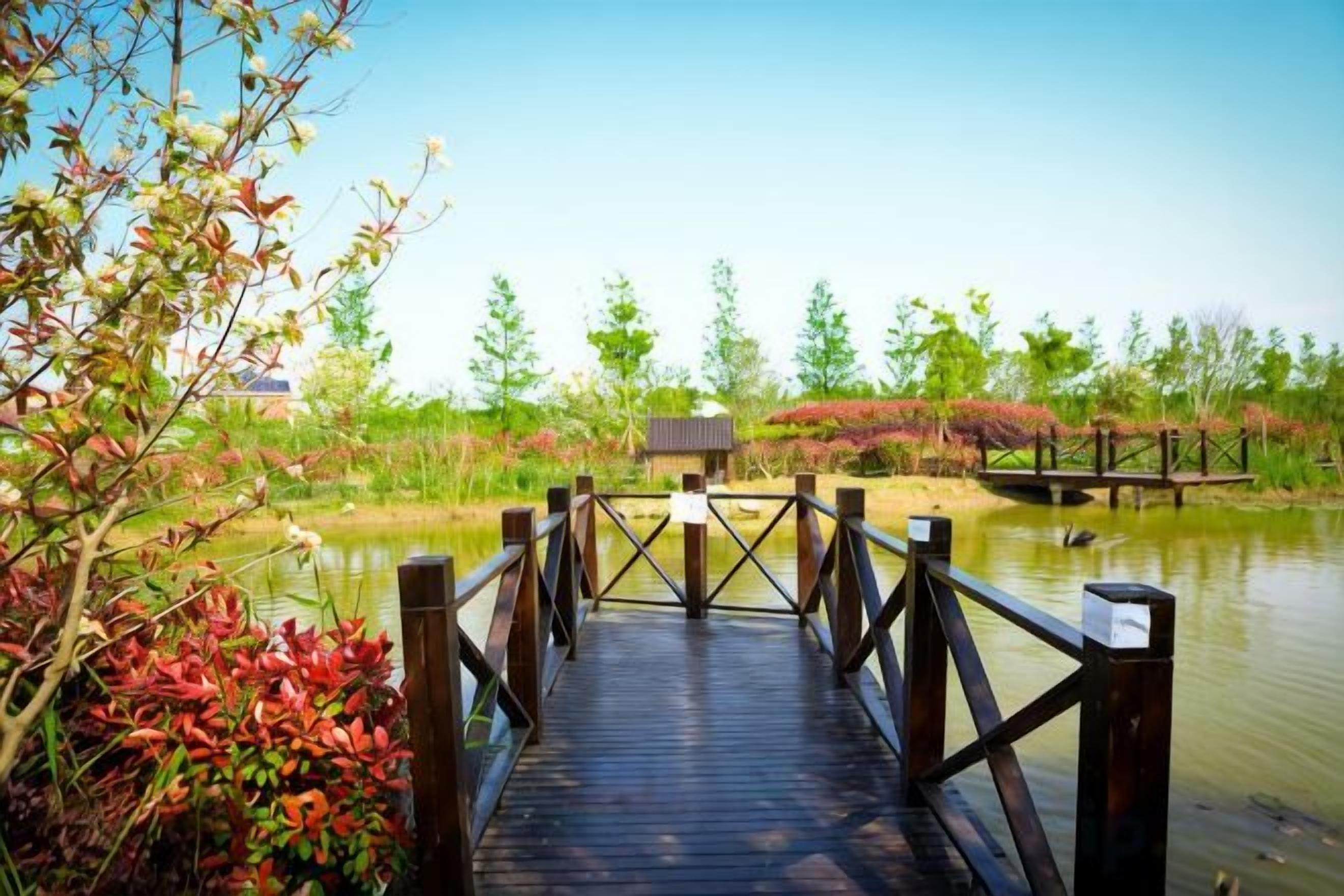 A wooden bridge over a body of water with a small building in the background.