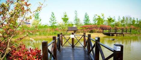 A wooden bridge over a body of water with a small building in the background.
