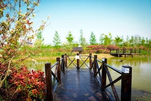 A wooden bridge over a body of water with a small building in the background. - An Hengsha Isiand Resort Hotel (Shanghai)