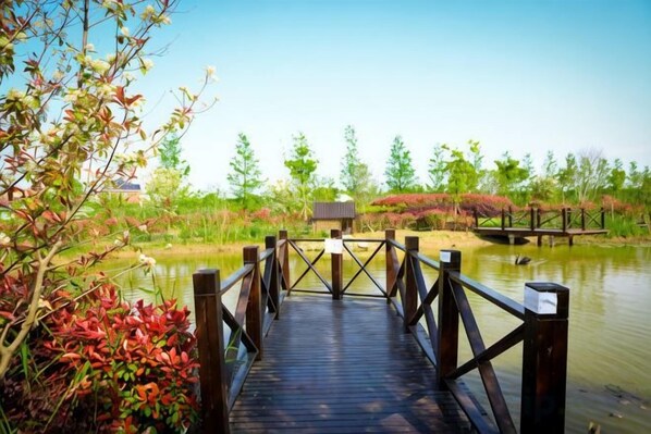 A wooden bridge over a body of water with a small building in the background. - An Hengsha Isiand Resort Hotel (Shanghai)