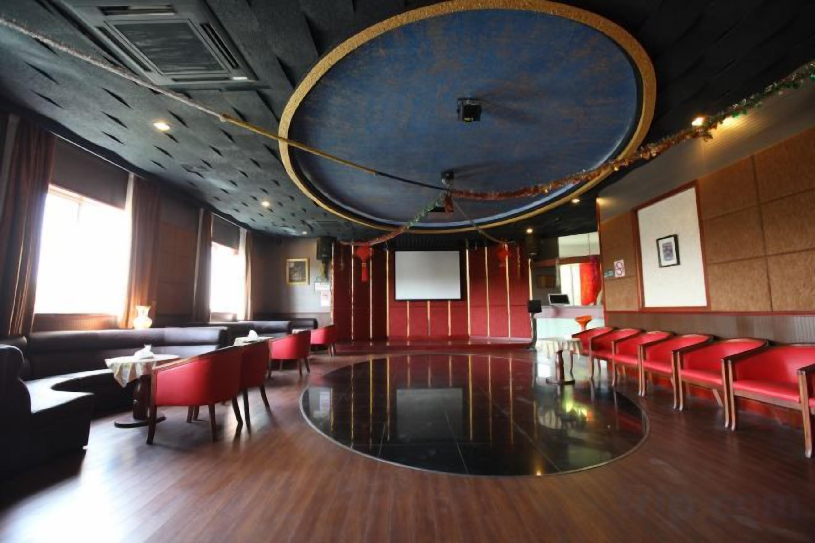 A conference room with a large screen, red seating, and a polished floor.