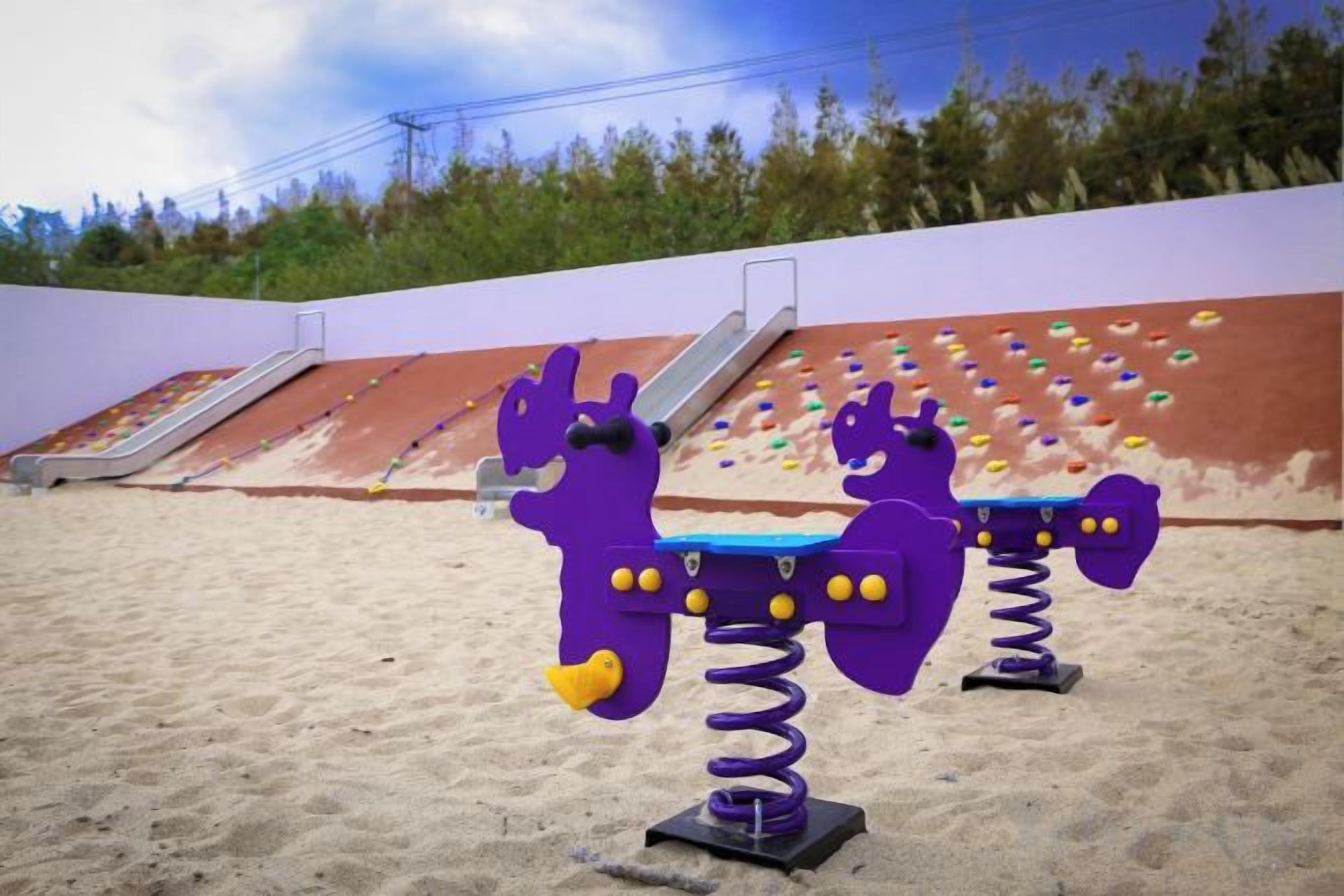 Outdoor playground equipment with slides and climbing holds.