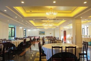 A spacious dining area with multiple tables and chairs, a chandelier, and a view of the outdoors. - An Hengsha Isiand Resort Hotel (Shanghai)