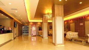 A hotel lobby with a reception desk, a chandelier, and a seating area with a covered table. - An Hengsha Isiand Resort Hotel (Shanghai)