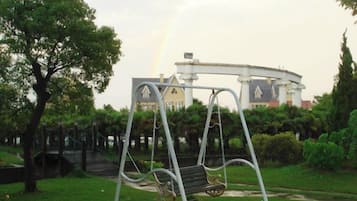 A park with a swing set and a building in the background.