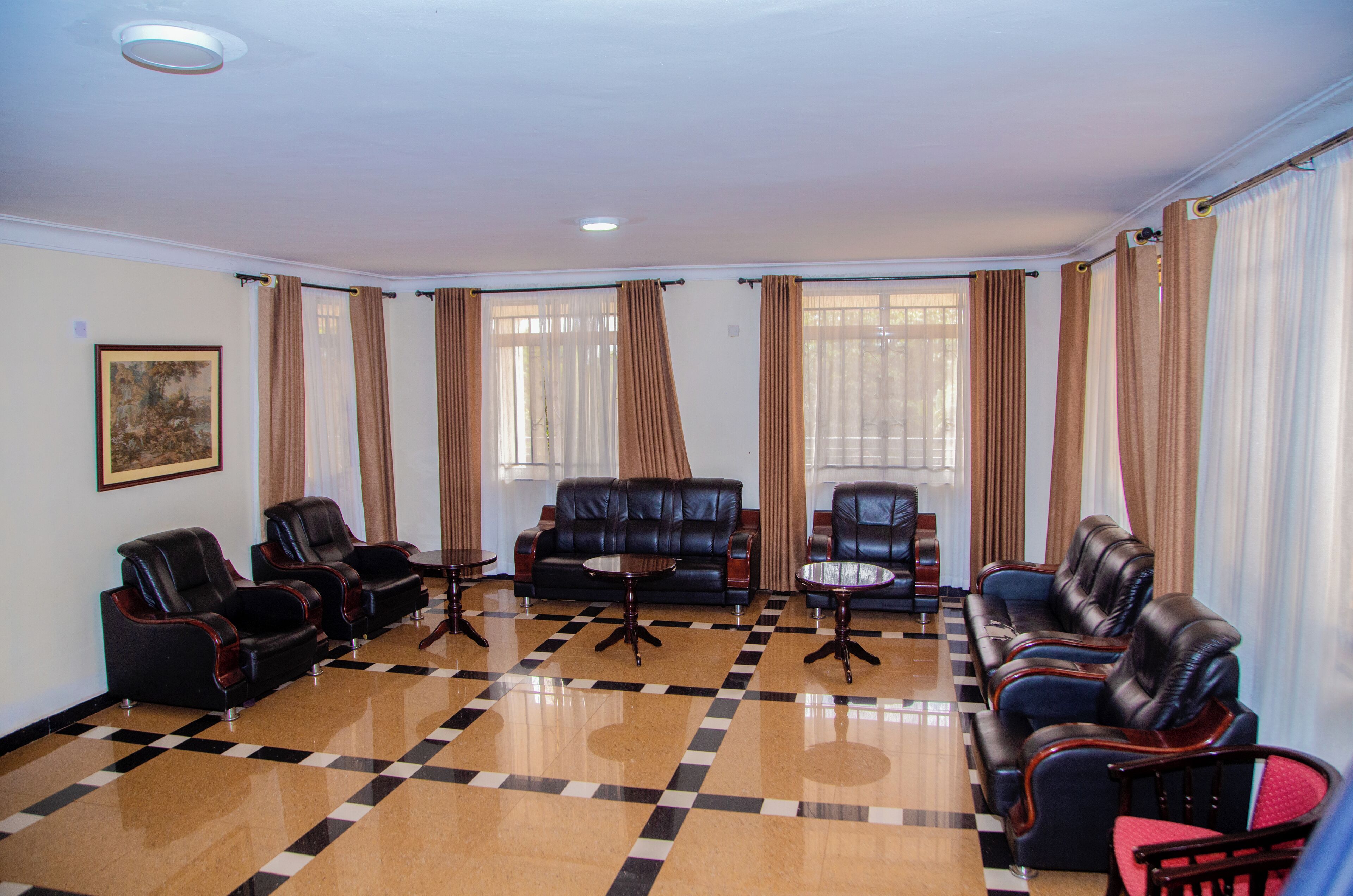 Una hall con pavimento a scacchi, divani in pelle e tende.