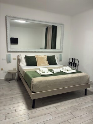 A neatly made bed with a green bedspread, white pillows, and a beige throw.