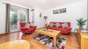 A living room with a red sofa set, a wooden coffee table, and a patterned rug. - Super Prime Train Station Inverkeithing by Three Bridges Apartments (Inverkeithing)