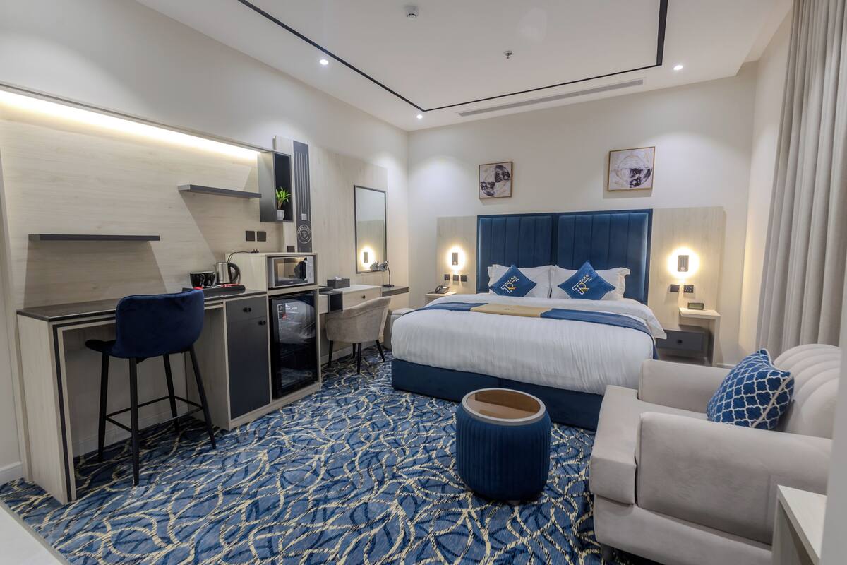 A modern hotel room with a large bed, a desk, and a chair.