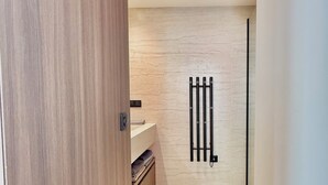 Un baño moderno con tocador de madera, toallero y piso de baldosas en tonos claros.