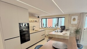 Una cocina moderna con una isla central, electrodomésticos integrados y una zona de comedor con mesa de madera.