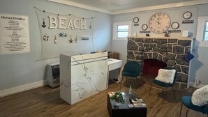 A room with a stone fireplace, a desk, and a 'BEACH' sign on the wall. - Blue Little Havana (Miami)