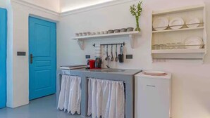 A compact kitchen with a blue door, a coffee machine, a kettle, and a refrigerator. - Cycladic Traditional House with view by MPS (Emporio)