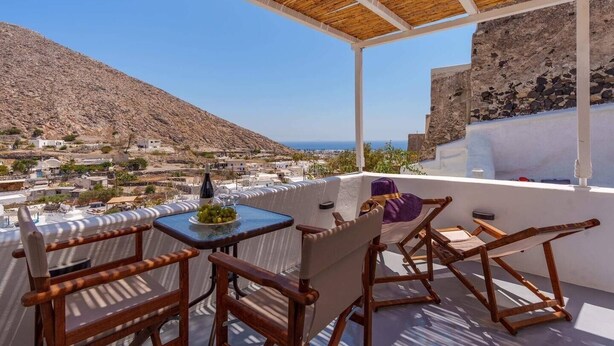 A terrace with a table set for two, overlooking a coastal village and a mountain. - Cycladic Traditional House with view by MPS (Emporio)