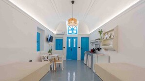 A modern hotel room with a kitchenette, a dining area, and a large window with a blue door. - Cycladic Traditional House with view by MPS (Emporio)