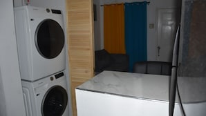 A compact room with a washing machine, a small table, and a door with a curtain.