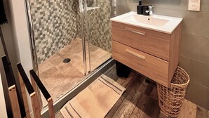 A modern bathroom with a glass shower enclosure, a wooden vanity, and a tiled backsplash. - Cocooning in Cognac (Cognac)
