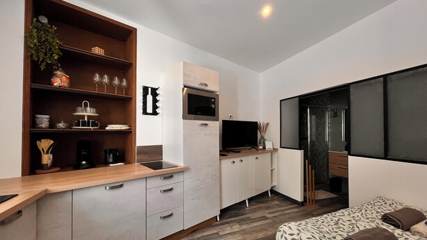 A modern kitchen with a wooden countertop, built-in appliances, and a dining area with a bench. - Cocooning in Cognac (Cognac)