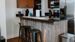 Une cuisine moderne avec des meubles en bois, des appareils électroménagers en acier inoxydable et un coin bar avec des tabourets.