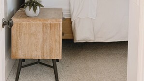 Une chambre à coucher avec un lit, une table de chevet avec une lampe et une petite plante en pot.