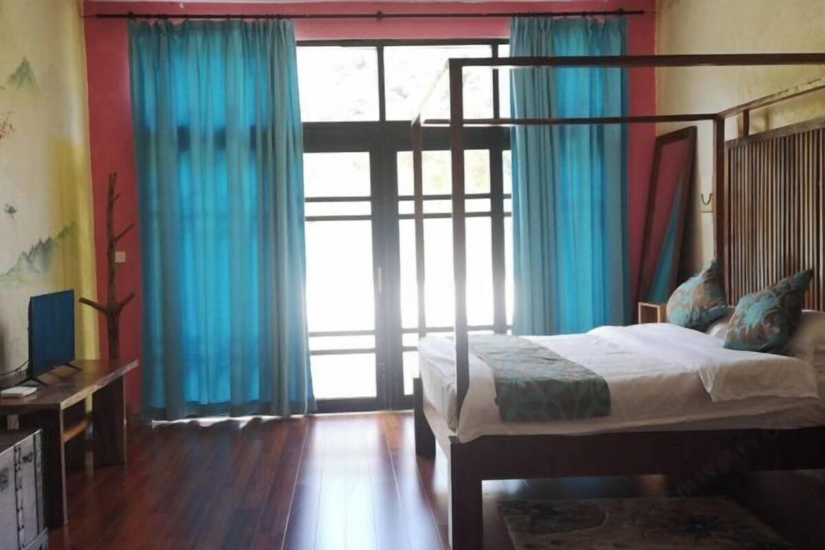 Un dormitorio con una cama, un escritorio y una silla. Hay una ventana con cortinas.