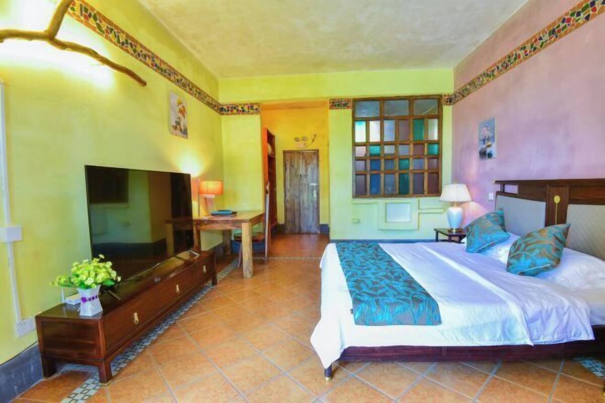 Una habitación de hotel con cama, televisión, escritorio y ventana.