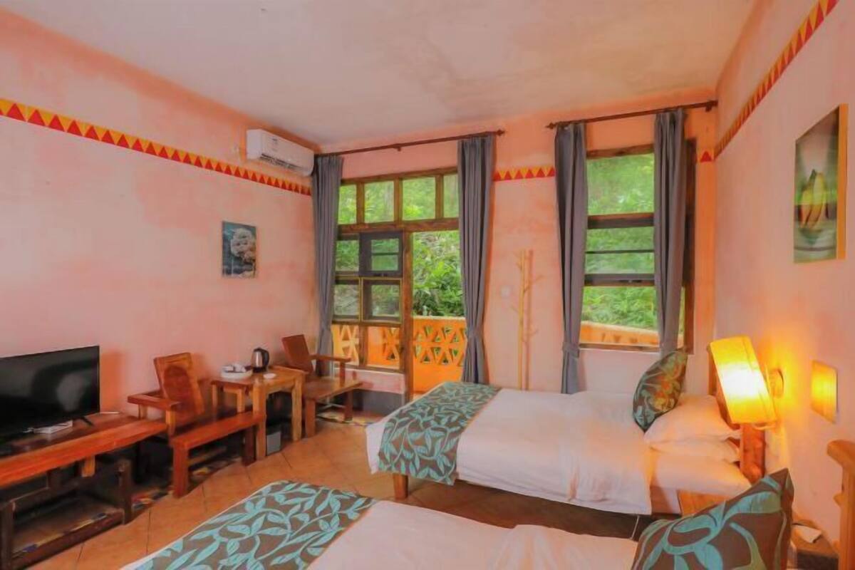 Habitación de hotel con dos camas, televisión, escritorio y una silla.