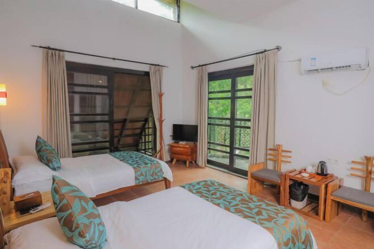 Habitación de hotel con dos camas, televisión, escritorio y una silla.