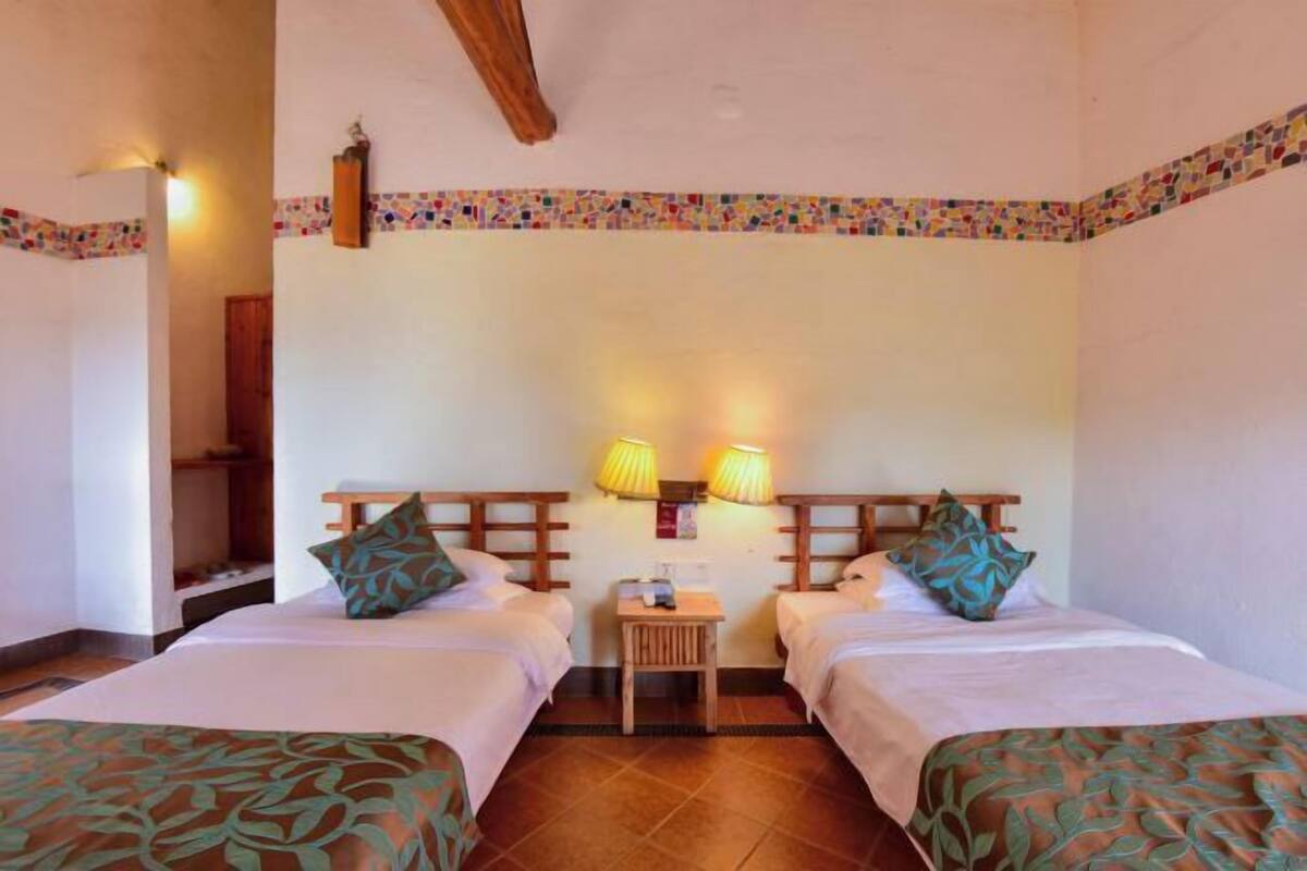 Una habitación de hotel con dos camas, una mesita y dos lámparas de pared.