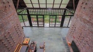 Une terrasse sur le toit avec des murs en briques, un espace salon couvert et une vue sur la verdure.