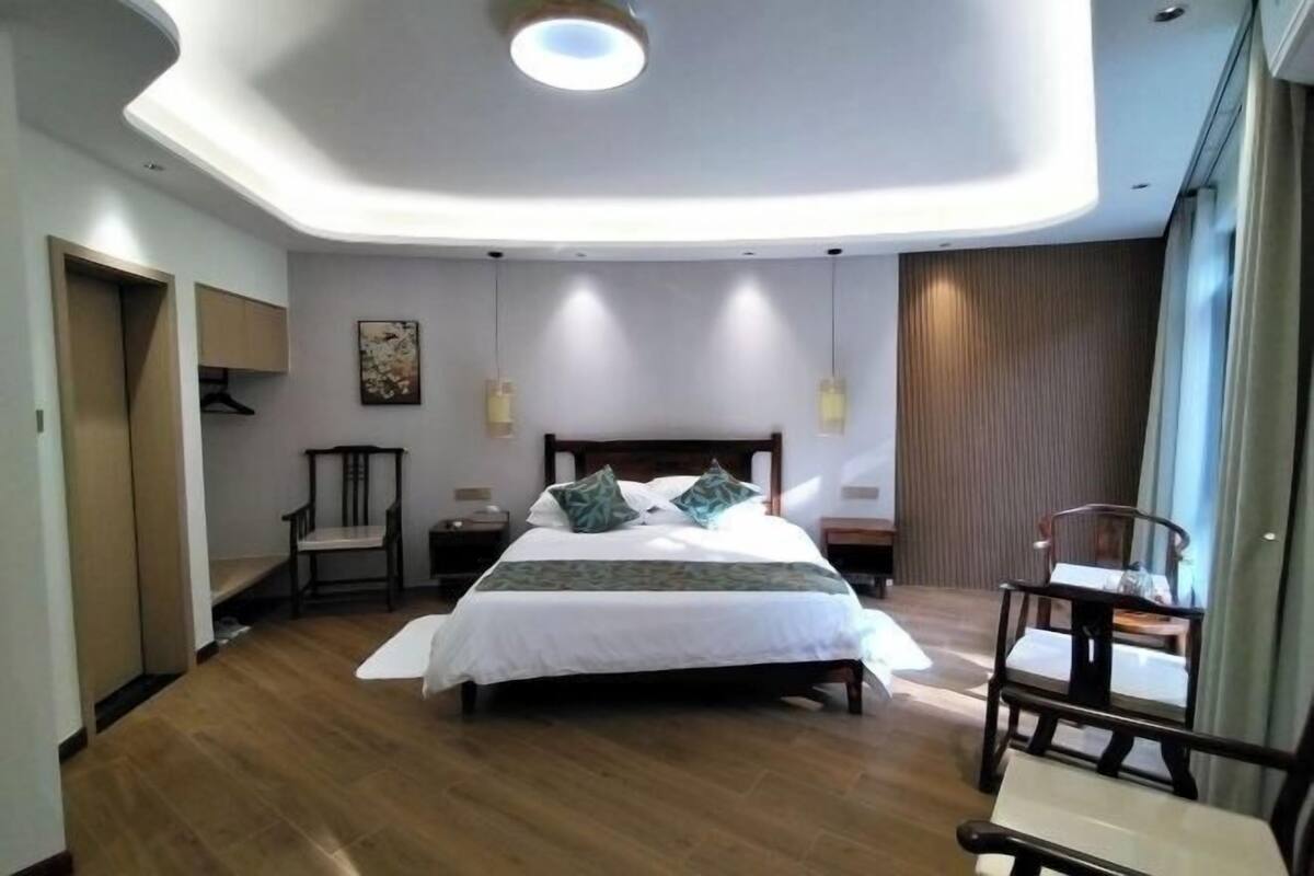 Un dormitorio moderno con una cama grande, suelo de madera y un diseño de techo original.