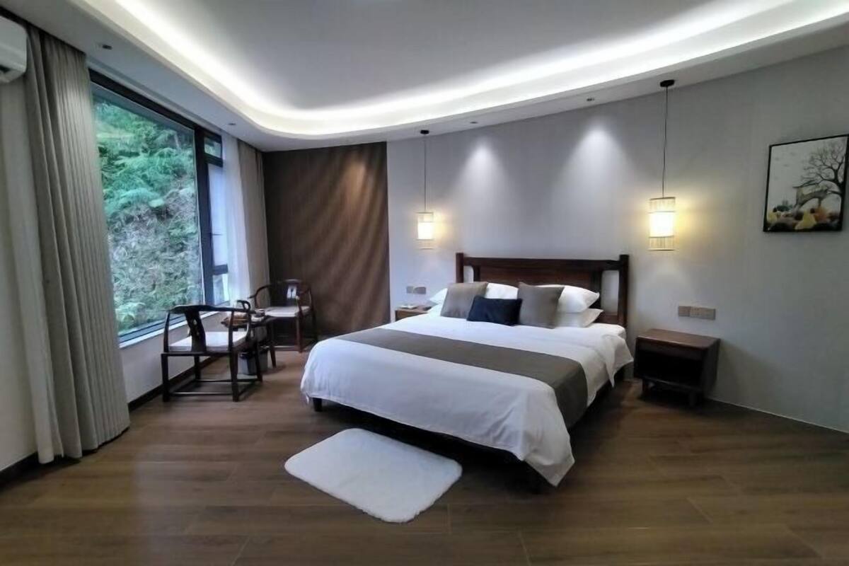 Habitación de hotel moderna con una cama grande, un escritorio y vistas al exterior.