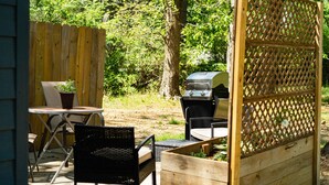 Eine Terrasse mit Tisch und Stühlen, einem Grill und einem Holzzaun.