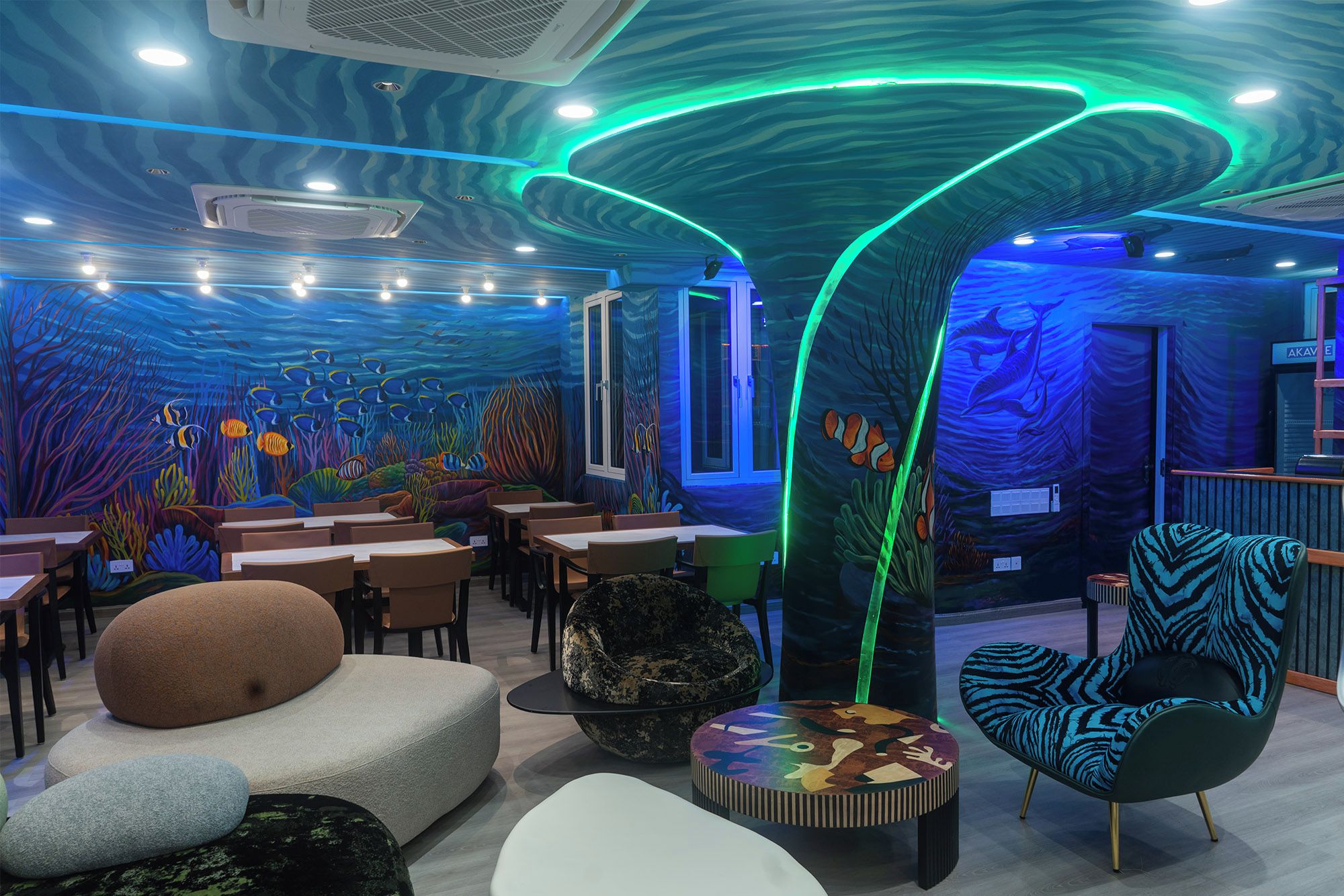 Un comedor interior con un diseño de techo original, mesas, sillas y un mural vibrante.