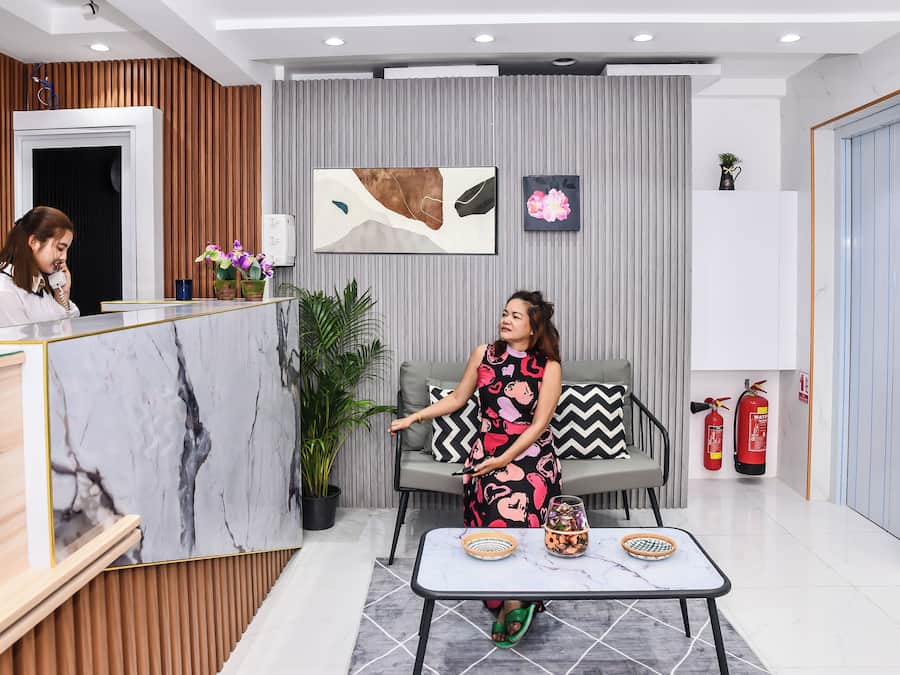 A reception area with a wooden reception desk, a sofa, a coffee table, and a potted plant.