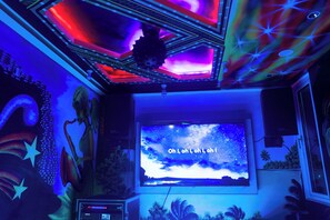 A room with a large screen displaying a starry sky, a sound system, and a ceiling with a geometric design. - LemonRock Comfort (Male)