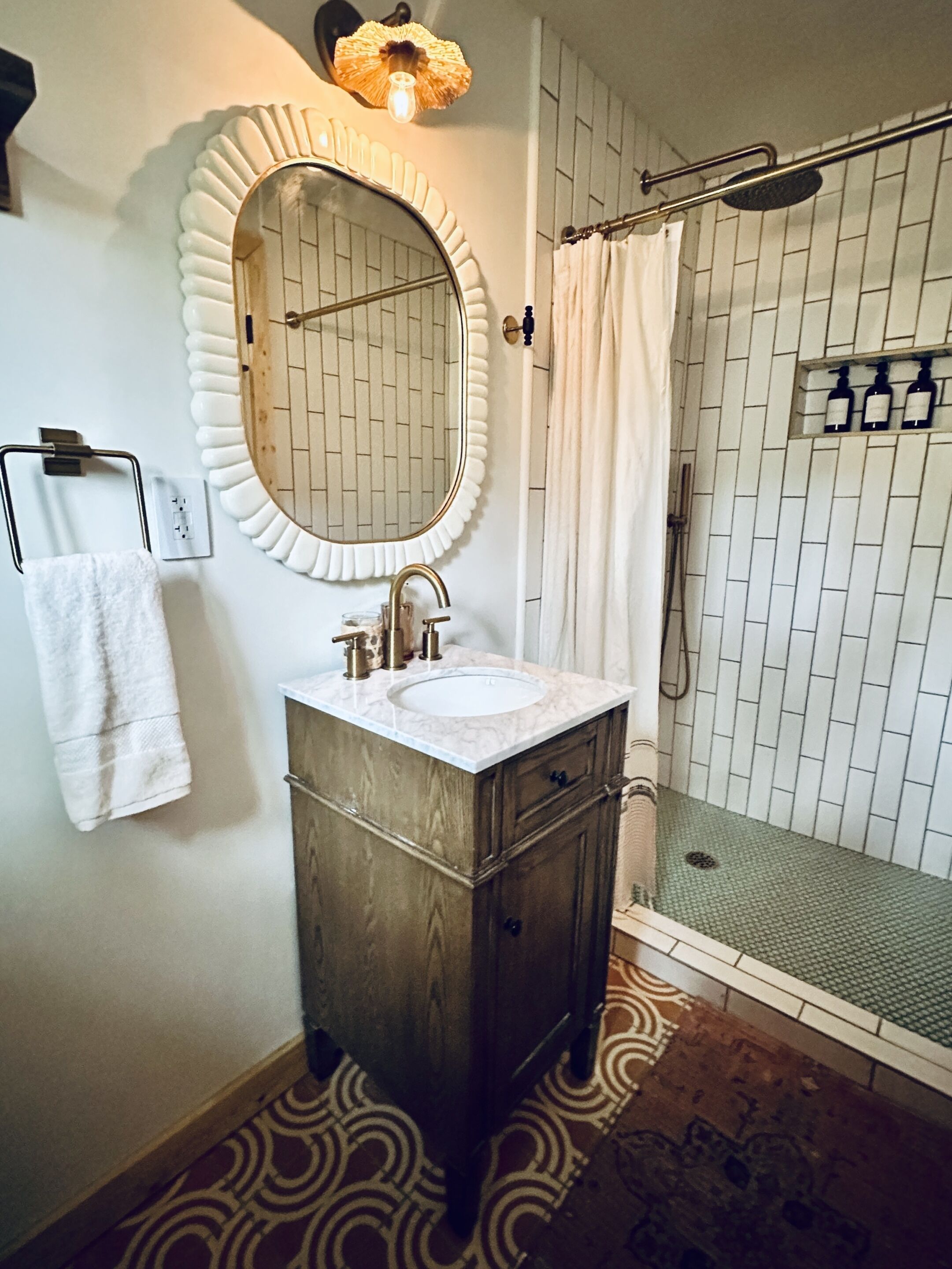 A bathroom with a round mirror, a sink, and a shower.