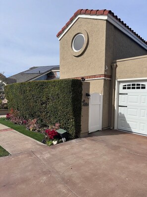 A residential house with a beige exterior, a white garage door, and a well-maintained hedge. - Studio in Quiet Gated SFR Community (Laguna Niguel)