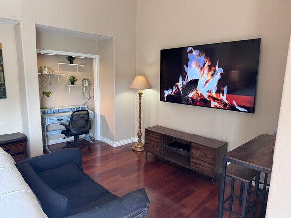 A living room with a flat-screen TV, a sofa, a coffee table, a lamp, and a TV stand. - Studio in Quiet Gated SFR Community (Laguna Niguel)