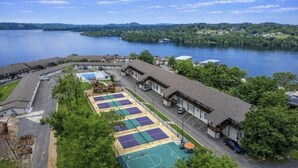 Un hotel junto al lago con cancha de tenis, piscina y estacionamiento.