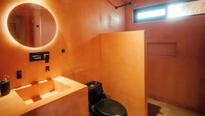 A bathroom with a round mirror, a sink, and a toilet. - Penthouse with pool & ocean view (Puerto Escondido)