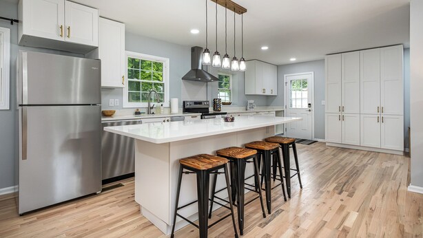 A modern kitchen with a large island, stainless steel appliances, and bar stools.