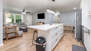 A modern kitchen with white cabinetry, a central island, and a stainless steel refrigerator.