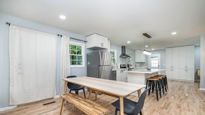 A modern kitchen with a wooden table, black chairs, and a built-in bench.