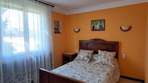 A bedroom with a wooden bed, a nightstand, and two wall-mounted lamps. - Country house near the Ardèche (Saint-Paulet-de-Caisson)