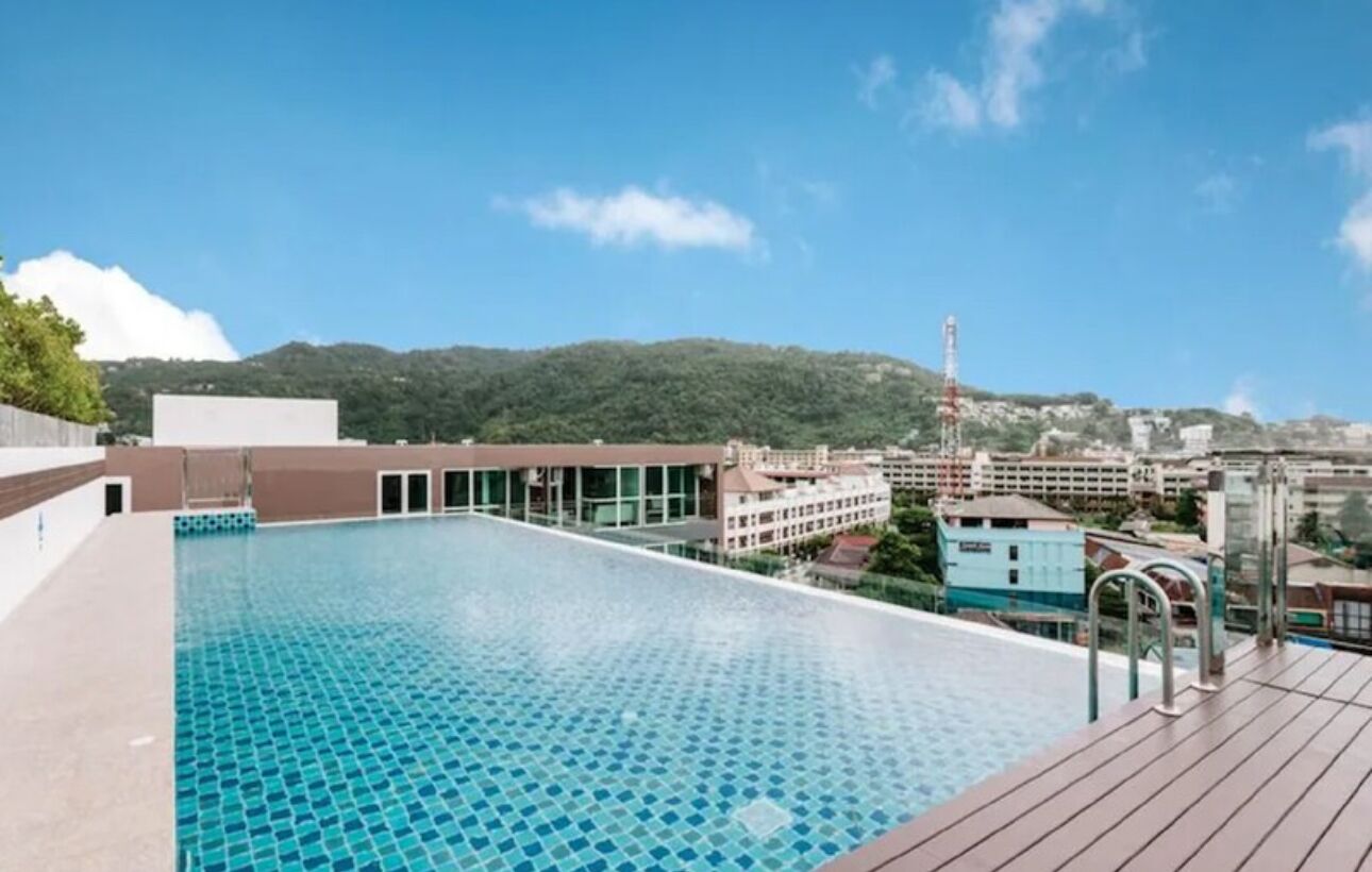 Piscina no terraço com vista clara dos edifícios e colinas ao redor.