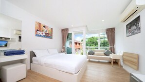 Une chambre d’hôtel moderne équipée d’un lit, d’un bureau, d’un canapé et d’une grande fenêtre donnant sur l’extérieur.