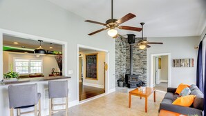 A spacious living room with a fireplace, a kitchen area with bar stools, and a ceiling fan. - 7 Mi to Dtwn: Family Retreat in Chattanooga (Chattanooga)